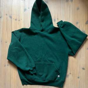 Mörkgrön russell athletic hoodie i storlek L. Riktigt bra passform, boxy och en aning croppad silhuett. Måttet på bilden är ungefärlig 