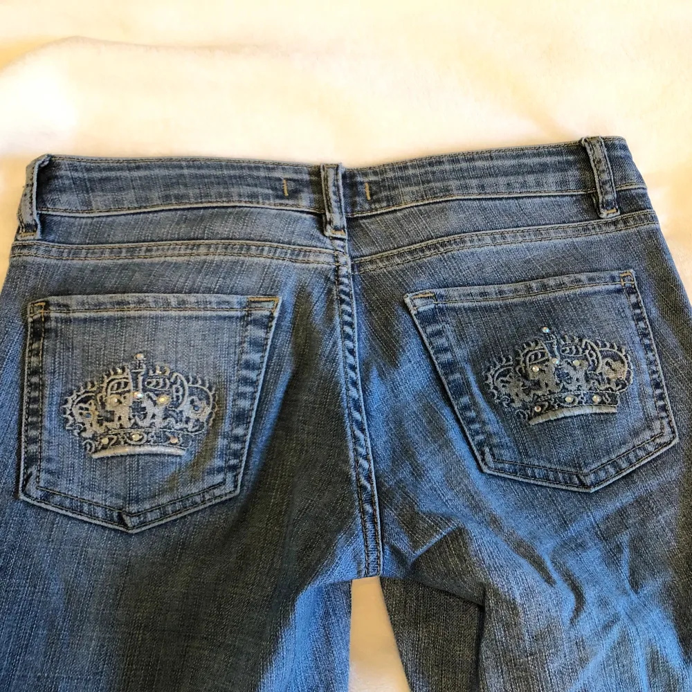 Jättefina jeans med kronor på bakfickorna och rhinestones. Dom är bootcut! Jättebra skick! Midjemåttet är 72cm och innerbenslängden är 82cm💕 tryck på köp nu 💕. Jeans & Byxor.