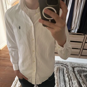 Vit Ralph Lauren skjorta - Säljer nu min Ralph Lauren skorta då den tyvärr blivit för kort i armarna, skjortan är använd ett antal gånger men är i toppskick, skriv om fler frågor finns! Köpt för 1300kr men jag säljer för endast 500!🤩