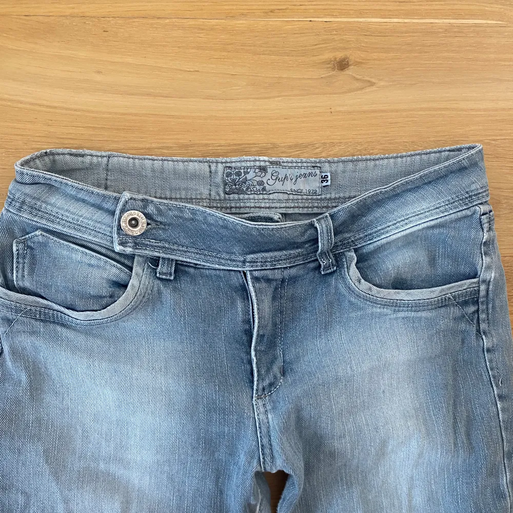 Jättesnygga lågmidjade jeans i ljusblå/grå, storlek 36/S med fina detaljer! Köpta second hand och välanvända men forfarande i väldigt bra skick. Jeans & Byxor.