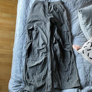 Byxor från WEEKDAY  - Det är är ett par byxor som är mörk gröna. Storlek 34. Det är polyamide material på byxorna. Snörning nedtill. Fickor vid sidorna av låren. Luftiga och sjöns. 