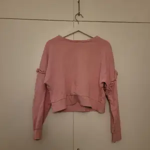 En rosa sweatshirt med ett litet hål på axeln (se bild 3). Går att sy ihop, syns inte så jättebra när man har på sig det eftersom det är ganska litet.
