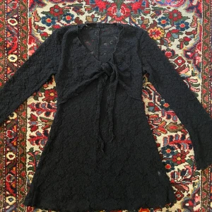 Svart spets-klänning - Köpt secondhand, utan märke tyvärr. Jättefin med ärmar som går ut lite och knytning vid bröstet
