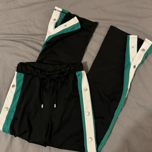 Byxor med knappar på sidorna - Tunna byxor med knappar på sidorna och vita / gröna streck. Storlek S. Aldrig använt. 