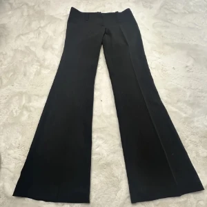 Lågmidjade kostymbyxor! - Lågmidjade svarta kostymbyxor! Faller jättefint på benen. Det är randiga men syns bara i vissa ljus! Midjemåttet är 37,5  och innerbenslängden är ungefär 83 cm