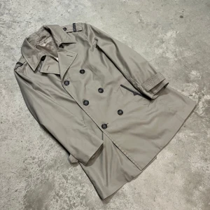 Versace Silk Lined Tranch Coat - Sidenfodrad Versace Trench Coat inköpt från en välkänd och trusted source i England (@19uj__militaria på instagram) för 1400. Använder den knappt då den va lite för liten på mig. Tveka inte att skriva om du har några ytterligare frågor