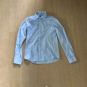 Blå kostymskjorta - Jack and Jones skjorta med en bastant krage och hål för manschettknappar storlek 152 barn