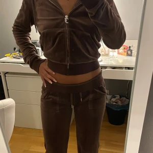 Brun hoodie i velour - En brun hoodie i velour med dragkedja framtill. Tröjan har långa ärmar och en huva. Den är croppad och har ribbade muddar vid ärmslut och nederkant.
