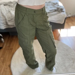 Khakigröna lågmidjade cargobyxor  - I storlek 34, men kan även användas för dem med storlek 36 eftersom att de är stretchiga. Säljer pga att de är oanvända och att de inte kommer till användning. De är lågmidjade och har en baggy/loose fit. 