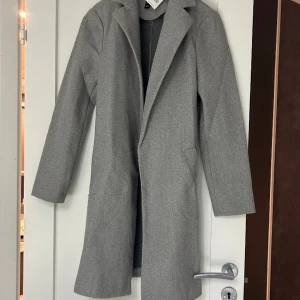 Kappa - Formel kappa från new look aldrig använd, skönt och bra material material. Normal i storlek och mycket fin grå färg. Sidfickor men inga knappor, man kan använda vanlig bälte istället. 