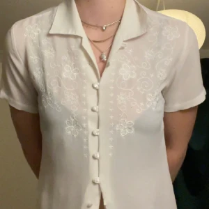 Vit blus  - Vit blus med fina detajer med blommor! Lite genomskinlig. Jätte fin och den är i fint skick!! S/M