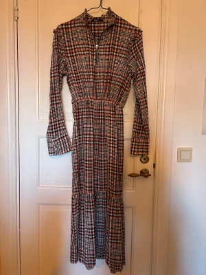 Rutig klänning - Oanvänd långärmad klänning i rutigt mönster med dragkedja. Storlek 34 från Gina Tricot.
