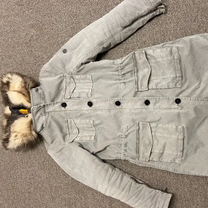 Parkas Blonde no 8 - Fin knälång mellansvenska parkas. Fodrad i fint foder som är avtagbart snabbt med dragkedja. Fin kapuschong o knappar och dragkedjor. Generöst med fickor.  Köpt för drygt 7000 kr. 