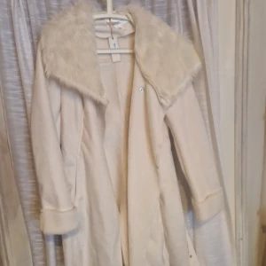 Snygg vårkappa - Ny och oanvänd vit kappa från bonprix. Hängt I garderoben några år men kommer aldrig till användning då stilen inte passade mig riktigt.  Lite fodrad, perfek till vår och höst.  Materialet påminner lite om mocka utvändigt och något slags konstpäls. 