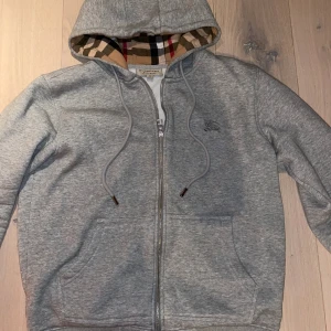 Burberry Ziphoodie  - Använd få gånger och den är 100% äkta. Kvitto finns och den är köpt på vestiarie collective för 3800kr. Hela Kvittot skickas i pm vid intresse. Den är i väldigt bra skick och det är en väldigt skön Ziphoodie.