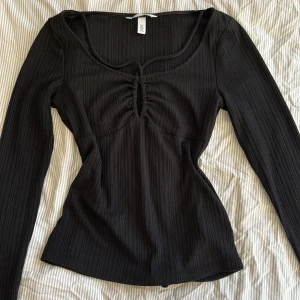 Svart topp med detaljer - Jättefin figurnära svart topp med ribbad-liknande struktur och detaljer från H&M💓Endast använd ett fåtal gånger, inga defekter. Jättefin till vardags med ett par jeans men lika fin att styla till fest💋Tryck gärna på köp nu!☺️
