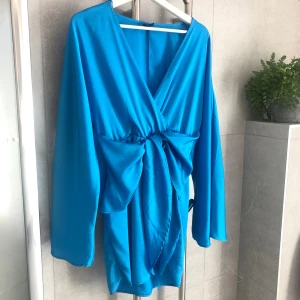 Klänning Rosie dress Gina Tricot - Underbar blå färg.💙 Nypris 599kr. Klänningen är använd 2 gånger, på enstaka ställen lyckades små små trådar/ slitage uppkomma på tyget. (Se exempel på bild 3)  Dock inget som jag personligen tycker stör.   Återkom vid frågor💙