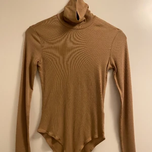 Beige ribbad body - Tunn, beige och ribbad body med polokrage från H&M. Aldrig använd. Storlek XS
