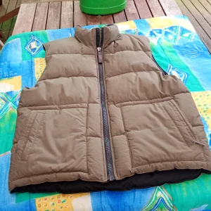 Tjock väst i stl L.Batistini. - Mycket fin väst kakhi stl L med dragkedja och fickor fram.av märket Batistini o inköpt hos Dressman.i nyskick obetydligt använd.inget slitage .