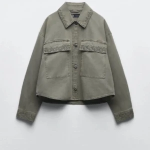 Grå jeansjacka - En grå jeansjacka med krage och knappar framtill. Jackan har två stora bröstfickor med lock och dekorativa detaljer på fickorna och ärmsluten. Den har en rak passform och är långärmad.