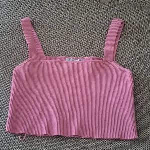 Rosa ribbad linnetopp - En rosa ribbad linnetopp med breda axelband. Toppen är ärmlös och har en tight passform.