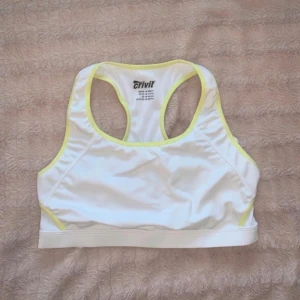 Vit sport-bh  - Vit sport-bh med neongula detaljer från Crivit i storlek Medium. Har använts max 3 gånger. Mycket bra skick.