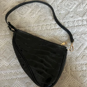 Svart liten väska  - Svart väska med guldiga detaljer. Inköpt för några år sedan. Använd x antal gånger men som ny. 
