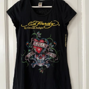Ed Hardy love kills slowly - Använd  max 3 ggr. Äkta Ed Hardy love kills slowly med rhinestones. Från designern Christian Audigier. Mini dress men han användas mer som lång t-shirt.  Kommer från fräscht rök och djurfritt hem