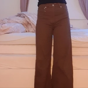 Bruna byxor - Ett par bruna jeans med hög midja och vida ben. Byxorna har en dragkedja och knappar framtill. Köpta på H&M 2021 och har ej använts sen dess. Säljer pga att jag har ej ngn användning för dem + dem är för stora. Säljer för 100 men går att pruta ner. DM för mer bilder
