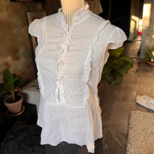 Blus - Blus med volanger. Ingen lapp hittas så därför ingen märke eller storlek. Den uppskattas till storlek s-m