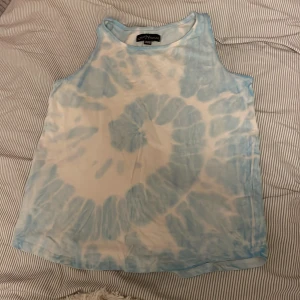 Blå och vit batikmönstrad linnetopp från XOXO Friends - En blå och vit batikmönstrad linnetopp från XOXO Friends. Toppen är ärmlös och har en avslappnad passform.