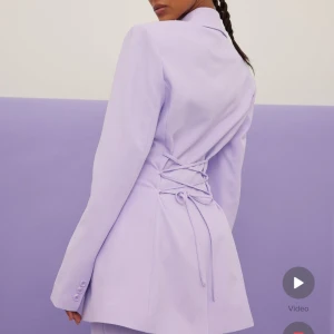 Lila kavaj/blazer från nakd - Säljer denna fina kavaj/blazer från nakd i en fin pastell lila färg. Den är helt oanvänd med lappen kvar och är i storlek 36. Fin detalj på ryggen med stören som går att knyta och spänna åt så som man önskar. Köparen står för frakt💕