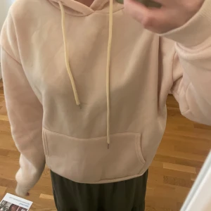 Beige hoodie från Shein - En beige hoodie från Shein med en stor ficka framtill och en tryckt design på baksidan med texten 'Face to the Sun' och en björn. Hoodien har en justerbar snöre vid huvan och är tillverkad av 100% polyester. Använd fåtal gånger och i bra skick. 