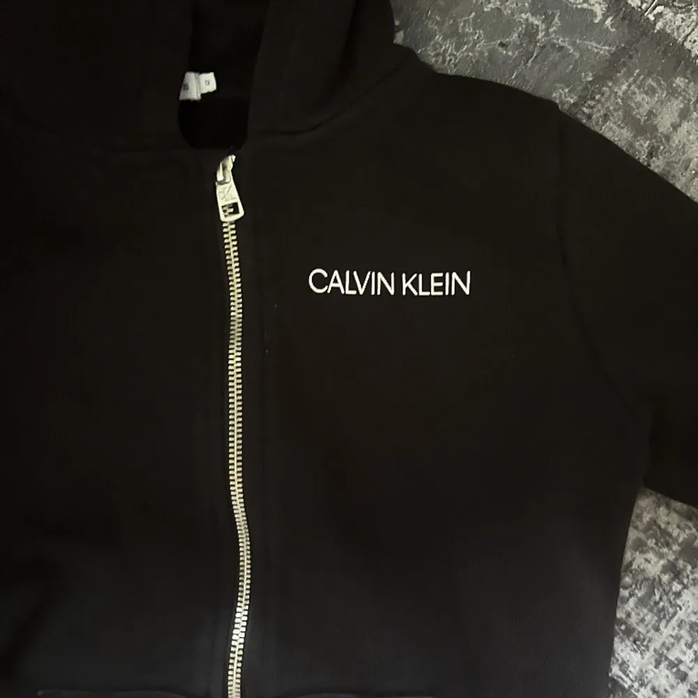 Säljer min Calvin Klein zip hoodie då den är väldigt liten för mig. Den passar folk som är 150-155. Köpte den förra året men slutade använda den efter sommaren pga att den va så liten. Pris går att diskutera. Skulle säga att den är i bra skick😊. Hoodies.