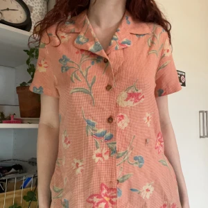 Rosa gingham blus piretta - Rosa blus i gingham/rutight mönster med brunfläckiga knappar hela vägen ner, storlek inte angiven men ungefär S/M. Lätt tyg och lös men strukturerad i passformen.