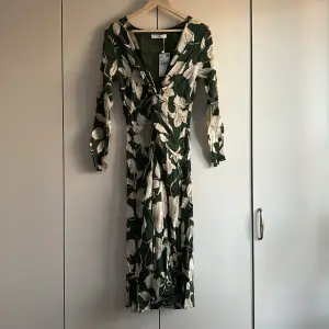 Underbar blommig klänning i midilängd, köpt på Mango. Grön med off white blommor. 100 % viskos. Nypris 599 kr.
