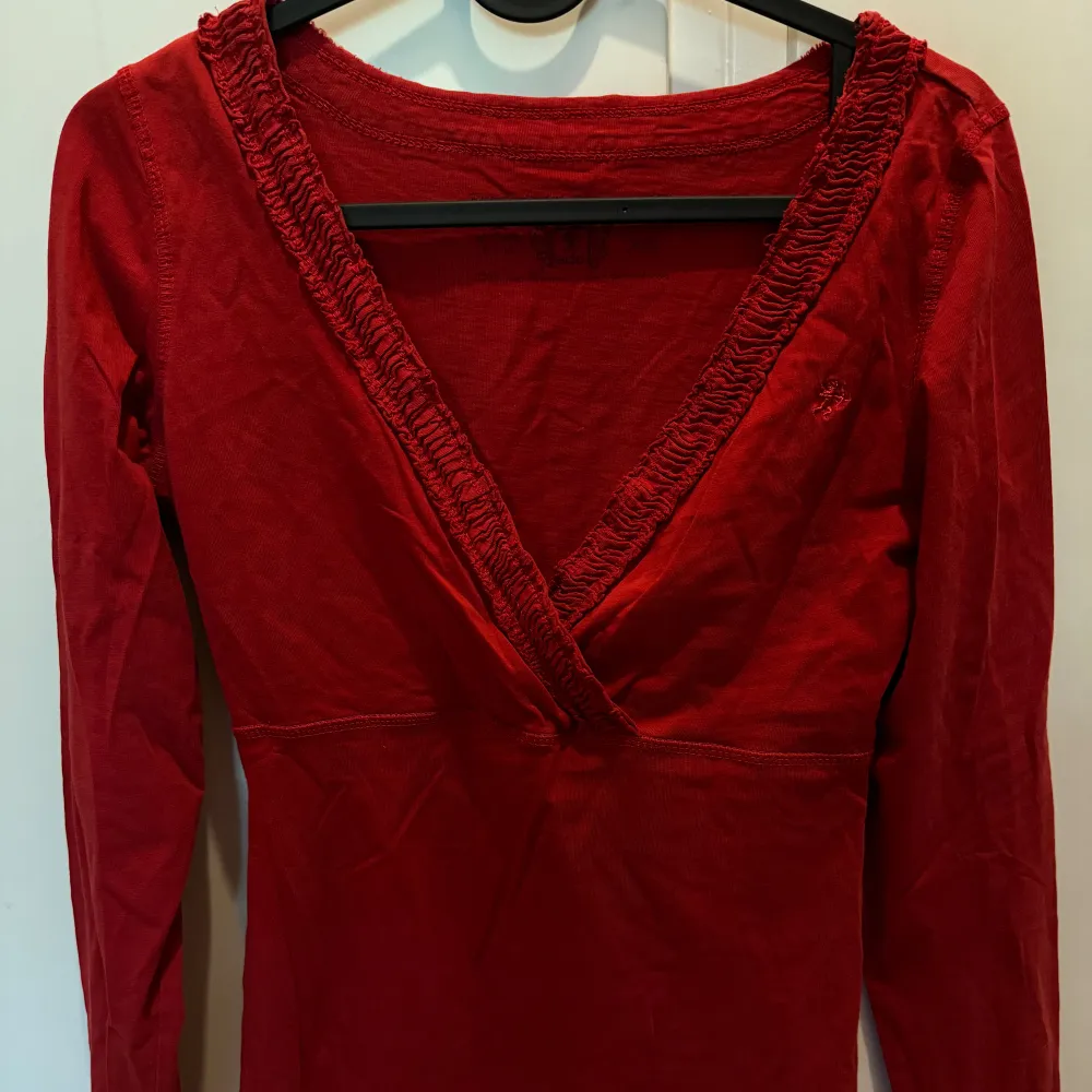 Säljer denna snygga v-ringade mörkare röda tröja då den är för tajt i armarna för mig tyvärr . Tröjor & Koftor.