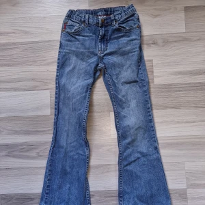 Blå jeansbyxor - Ett par blå jeansbyxor med bootcut-stil. Byxorna har en klassisk femficksdesign och är tillverkade i denim. Från Polarn O Pyret i storlek 134