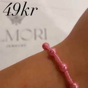 Rosa pärlarmband - Ett rosa pärlarmband med små, glänsande pärlor. Armbandet är enkelt och elegant, perfekt för både vardag och fest.