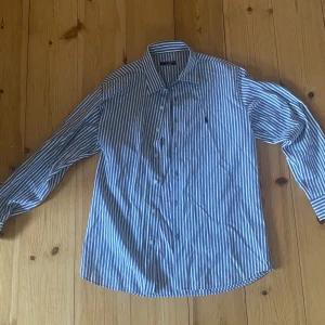 Ralph lauren skjorta  - Blå/grå randig Ralph lauren polo skjorta i bra skick, står att den är storlek L men sitter lite mer som M