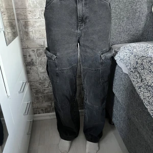 Svarta cargo jeans  - Svarta baggie cargo jeans ifrån H&M. Helt okej kvalitet, inte använda så många gånger. Originalpris 400kr.