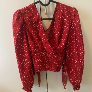 Sommar blus - En skön röd sommar blus med vita prickar. Storlek S (36). Oanvänd. Två fina detaljer vid både sidorna.