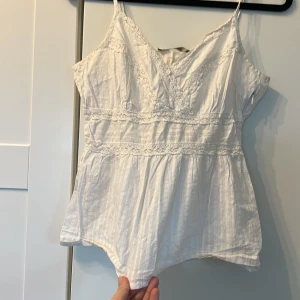 Vitt spets linne - Fint spets linne i god kvalitet, justerbara axelband samt en dragkedja i midjan för att få en fin form.  Jätte skrynklig men drar i sidorna så att ni kan se hela materialet Materialet går att stryka! 
