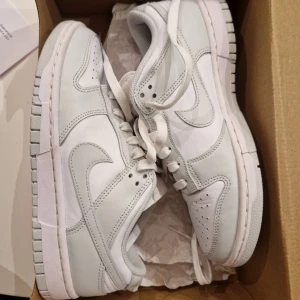 Nike Dunk ”Photon Dust” Low  - Säljer nu mina Nike Dunks i färgen Photon Dust, i modellen Low. Storlek 39. Köptes förra året i April på Merch Sweden men säljer nu för att dom är för små. De är endast använda en gång. Kvitto finns om det önskas. Just nu säljs dom för 3399 på deras sida.