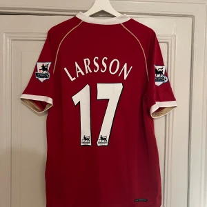 Henrik Larsson Manchester United Matchtröja 2007 - En reprint av Henrik Larssons matchtröja från hans tid i Manchester United under 2007. Henrik Larsson stod för ett krigande av vilja och löpningar som bidragande till att Manchester United vinner ligan denna säsong! Storlek L