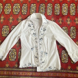 Skjorta - Jättesöt vit skjorta med blommigt broderi på. Har en liten ljusgul missfärgning på ena armen (bild 3) syns inte jättemycket skulle jag säga!