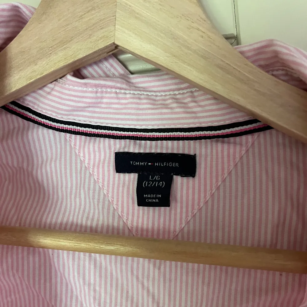Ljusrosa skjorta med vita ränder från Tommy Hilfiger, knappt använd. USA storlek (L 12/14 years) men skulle säga det är S💕ostruken på bilden  Köparen står för frakten💕 90kr. Paidat.