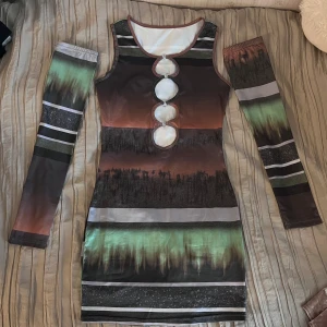 Klänning  - Klänning med detaljer. Tillkommer ärmar som man kan själv välja om man vill ha på sig i samband med klänningen eller inte. Aldrig använd! Så man kan ha klänningen i två olika modeller (se bilder). Sann i storlek. Stretchig.