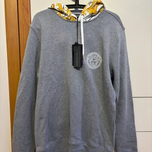 Versace hoodie  - Helt nytt skick, helt oanvänd.  Färg: grå Storlek: M Kvitto på vara finns vid önskemål. 