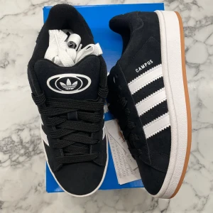 Adidas Campus 00s ”Black Gum” (Junior) - Helt nya och oanvända Adidas Campus 00s ”Black Gum” i juniormodellen. Storlek: 38 2/3. Pris: 1299+frakt. Skicka ett meddelande vid intresse. Köp tryggt och snabbt hos oss. Många nöjda kunder😊